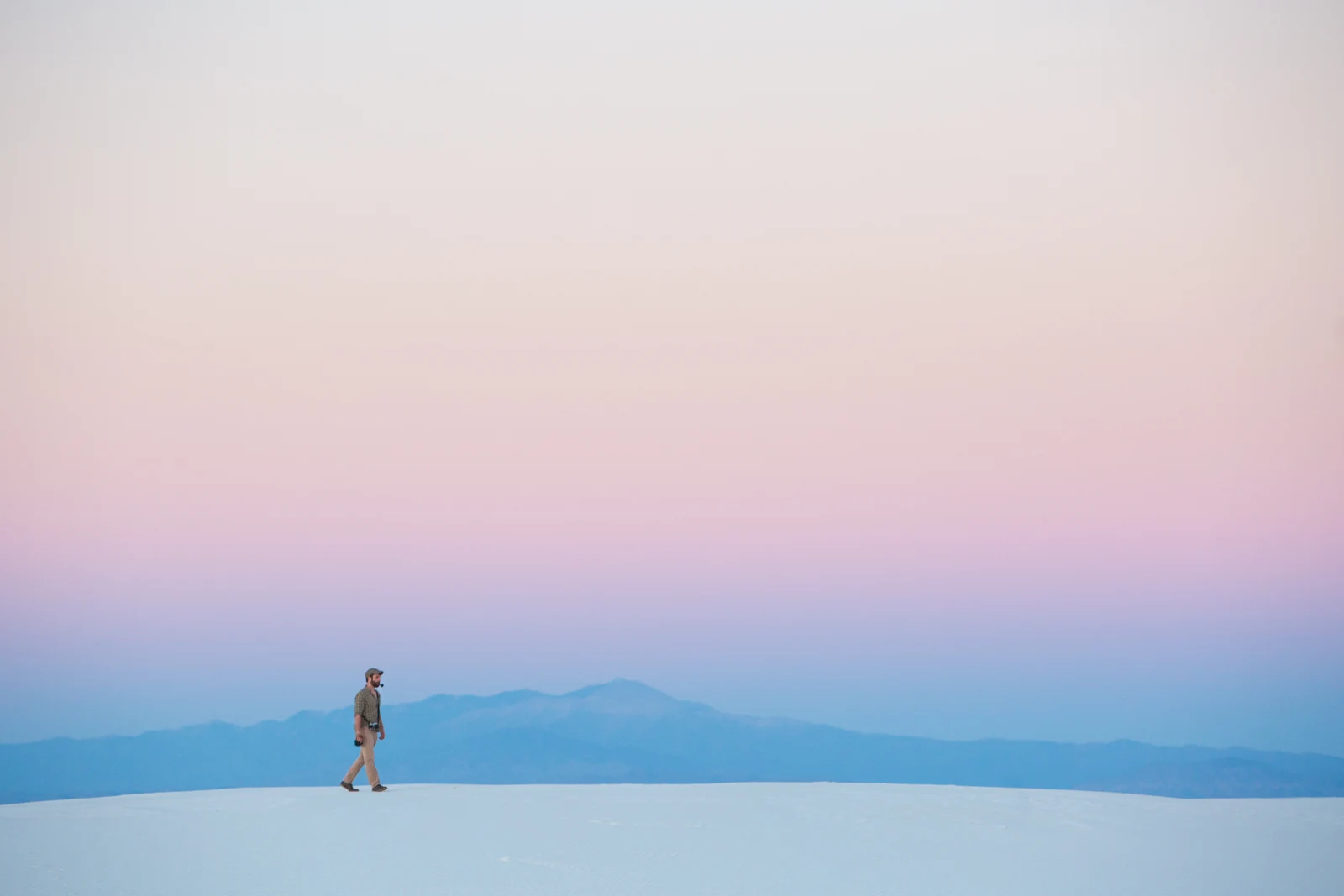 A hiker walking along a White Sands dune ridge at dusk